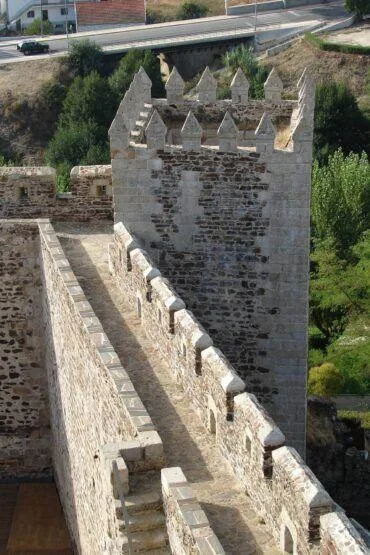 Torre medieval de pedra com ameias de granito branco, vista do parapeito interior com merlões quadrangulares.