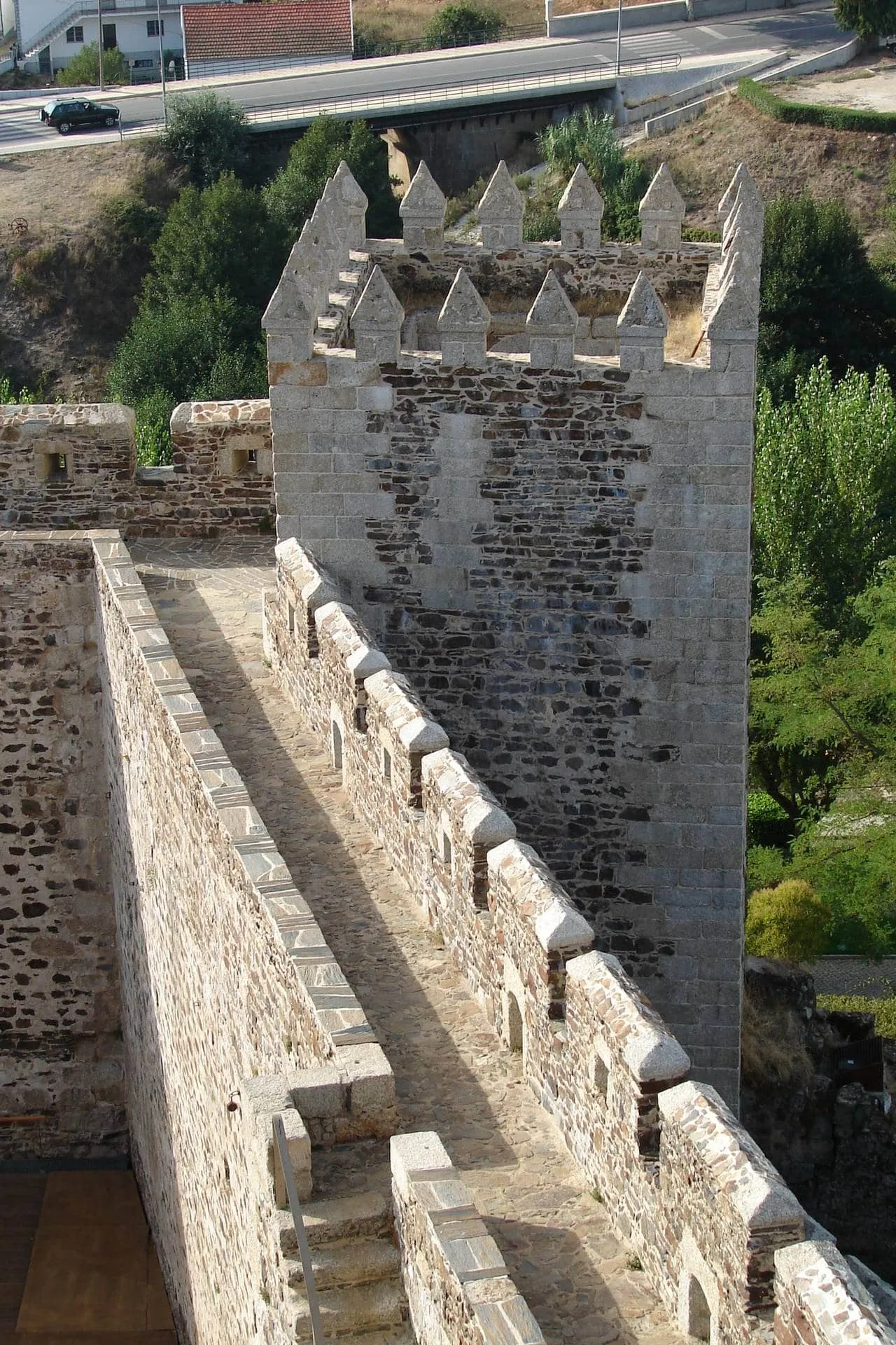 Torre medieval de pedra com ameias de granito branco, vista do parapeito interior com merlões quadrangulares.
